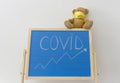 A child playroom with a teddy bear wearing medical mask and the growing graph of COVID-2019 cases drawn with chalk on a blackboard