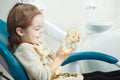 Child plays with artificial human jaw in dentist chair