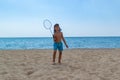 The child plays with a badminton racket and a shuttlecock on the beach