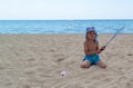 The child plays with a badminton racket and a shuttlecock on the beach.