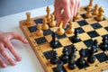 A child plays chess alone. Old wooden chessboard. Children`s hands. Chess pieces on a chessboard Royalty Free Stock Photo