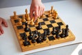 A child plays chess alone. Old wooden chessboard. Children`s hands. Chess pieces on a chessboard Royalty Free Stock Photo