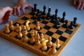A child plays chess alone. Old wooden chessboard. Children`s hands. Chess pieces on a chessboard Royalty Free Stock Photo