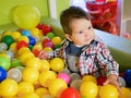 Child plays in colored balls. plastic balls in the playroom. Happy little kid boy playing at colorful plastic balls playground Royalty Free Stock Photo