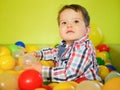 Child plays in colored balls. plastic balls in the playroom. Happy little kid boy playing at colorful plastic balls playground Royalty Free Stock Photo