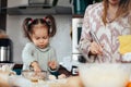 Child and adult cook together in kitchen making food with eggs and ingredients during morning hours on a weekend in a Royalty Free Stock Photo