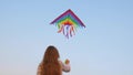 The child plays with a flying kite against the blue sky on a sunny day in summer. Colored kite with an hangs in air Royalty Free Stock Photo