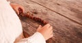 The child plays with the fruits of oak - brown acorns on a wooden table. Autumn gifts. Tree fruits