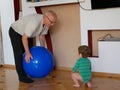 The child plays with the grandfather a ball. play a big blue ball at home. A boy is playing with his grandfather Royalty Free Stock Photo