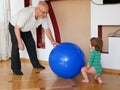 The child plays with the grandfather a ball. play a big blue ball at home. A boy is playing with his grandfather Royalty Free Stock Photo