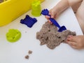 A child plays with kinetic sand: close up of baby hands with toy spatula and sand Royalty Free Stock Photo