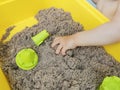 A child plays with kinetic sand: closeup of a child`s hand and sand Royalty Free Stock Photo