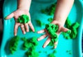 A child plays with kinetic sand. Hands of a child playing with green magic sand. Children`s creativity. Kinetic sand in a green Royalty Free Stock Photo