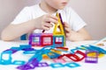 A child plays with a magnetic constructor on a white table. Building a toy house from blocks. Hands close up Royalty Free Stock Photo