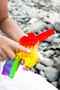 A child plays a multi-colored colorful pop it in the shape of a unicorn on a sea pebble beach.