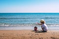 A child plays with a pink plastic bucket and shovel on the beach Royalty Free Stock Photo