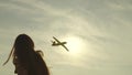 child plays a plane at sunset, girl launches flying toy plane into sky, childhood dream becoming pilot, adolescent