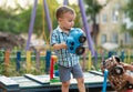 A child plays in the playground with toys in the sandbox. A toddler boy plays in the sand with a car on a summer day Royalty Free Stock Photo