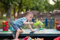 A child plays in the playground with toys in the sandbox. Toddler boy plays in the sand in the summer Royalty Free Stock Photo