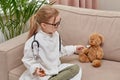 Child plays profession of doctor and feeds the toy teddy bear toy from a spoon. Royalty Free Stock Photo