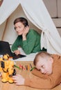 Child plays robot mom works laptop headphones