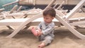 The child plays sits on the sand. A little boy on the beach near the river plays with his feet in the sand near the sun Royalty Free Stock Photo