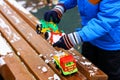 The child plays with the snow on the bench with toys. Royalty Free Stock Photo