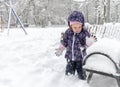 Child plays with snow in winter, little kid walks in snowy urban park
