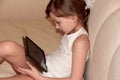 The child plays on the tablet lying on the bed