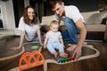 Child plays with wooden toy train and railroad in living room at home while sitting on floor with mom and dad,moving Royalty Free Stock Photo