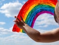 The child points to the painted rainbow symbol on the window. blue sky with clouds.