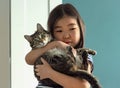 Child portrait with domestic pet, cute asian girl holding tabby cat Royalty Free Stock Photo