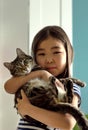 Child portrait with domestic pet, cute asian girl holding tabby cat Royalty Free Stock Photo