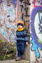 Child, posing in an old ruin building, sprayed with graffiti