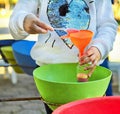 Child pour colored sand in the bottle