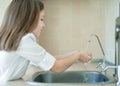 Child pouring fresh reverse osmosis purified water in kitchen at home. Drinking tap water. Consumption of tap water contributes to