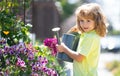 Child pouring water on the trees. Kid helps to care for the plants in the garden. Little boy with a watering can on Royalty Free Stock Photo