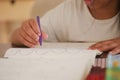 Child practicing handwriting with purple pen at home Royalty Free Stock Photo