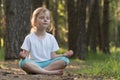 The child is practicing yoga in the forest