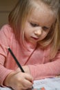 Child preschooler girl learns to draw and write in notebooks at home in the evening under the light from a desk lamp. Royalty Free Stock Photo