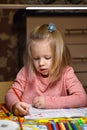 Child preschooler girl learns to draw and write in notebooks at home in the evening under the light from a desk lamp. Royalty Free Stock Photo