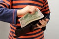 Child, preschooler, primary school student, puts money, banknotes, dollars, euros in a leather wallet, hands close-up