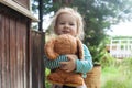 The child presses the little animal to his chest and smiles on a sunny day in the evening near the country house Royalty Free Stock Photo