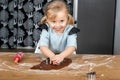 Child Pressing Cookie Cutter into Gingerbread Dough on Kitchen Table Royalty Free Stock Photo