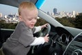 Child Pretends to Drive Car in Big City