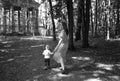 The child pulls her mother forward, holding her by the hem of the sundress in the Park on the path. Black and white photo.