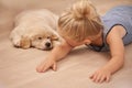 Child, puppy and hug with rest, floor and pet with love at house. Kid, dog and golden retriever or sleepy labrador with