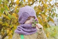 A child in a purple, knitted hat and scarf. Purple bouquet in hands