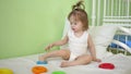 Child puts a toy ring on his foot. Baby playing in hospital on bed with pyramid and colored rings. Educational toys for Royalty Free Stock Photo