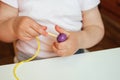 Child putting beads on a string. Bead stringing activity. Fine motor skills development